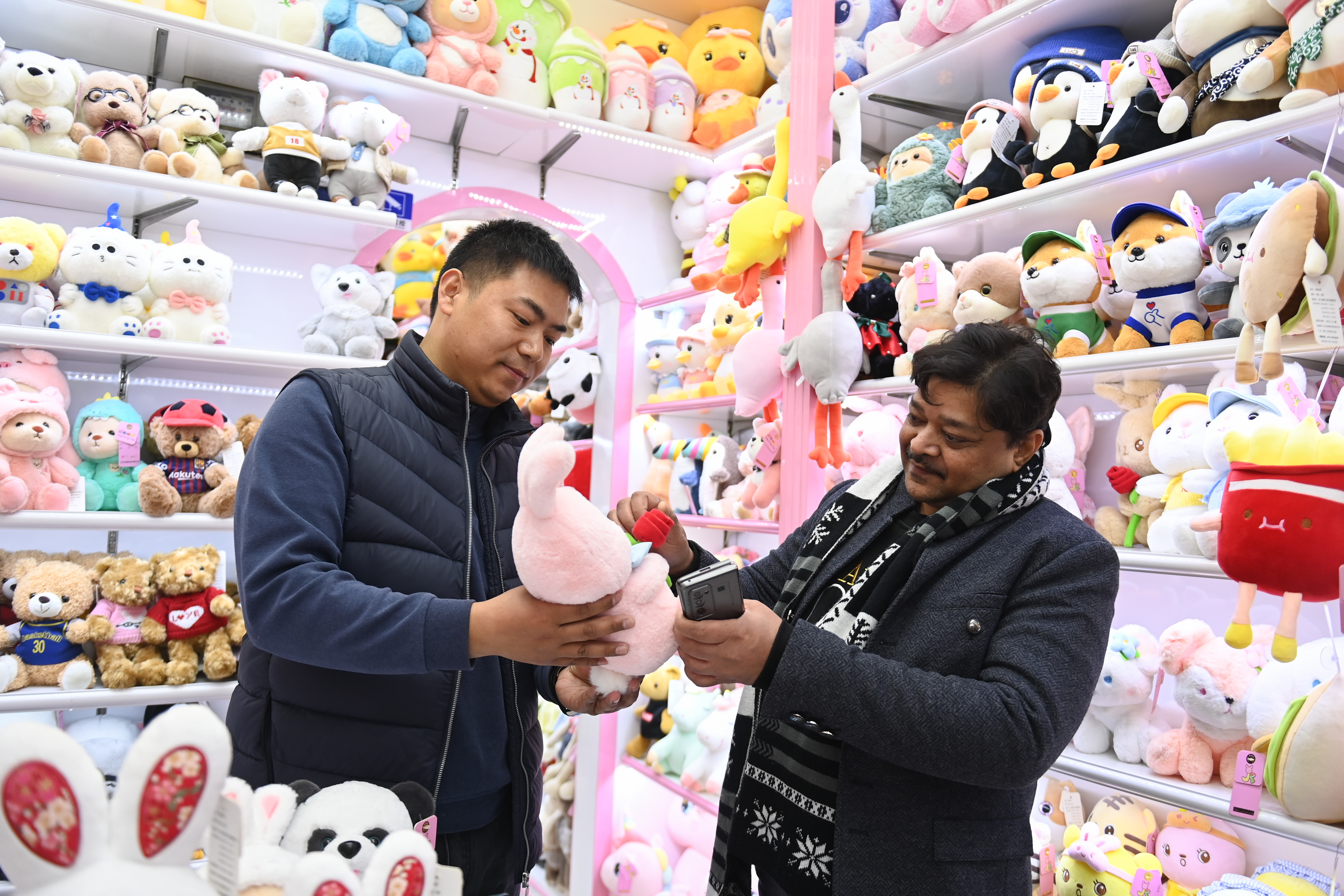 2023年2月2日，來自印度的客商（右）在義烏國際商貿(mào)城的一家玩具店鋪內(nèi)選購。